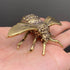 Brass bee figurine held in an open palm to show its palm-sized scale, veined wings, and textured thorax