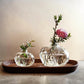 Clear glass pomegranate bud vase with a crown-shaped opening and pressed seed detail, on a white background