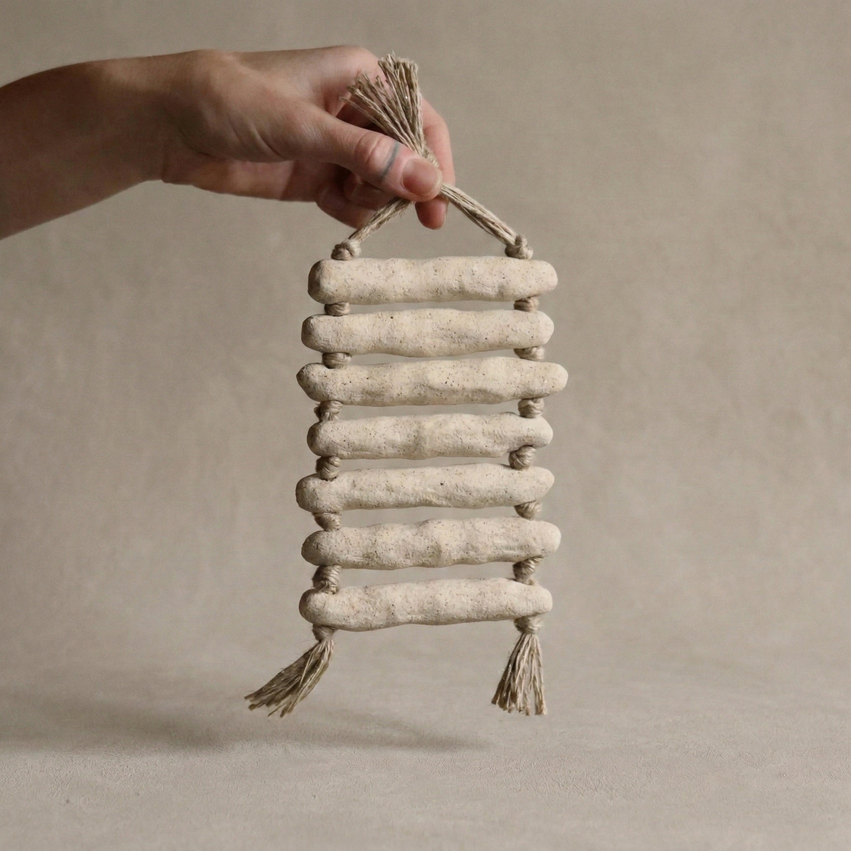 The Gathered Earth Wall Hanging with seven horizontal clay rungs showing raw unglazed texture and mineral variations, hand-built by Conrad and Dina in Canada, from WILLAGE