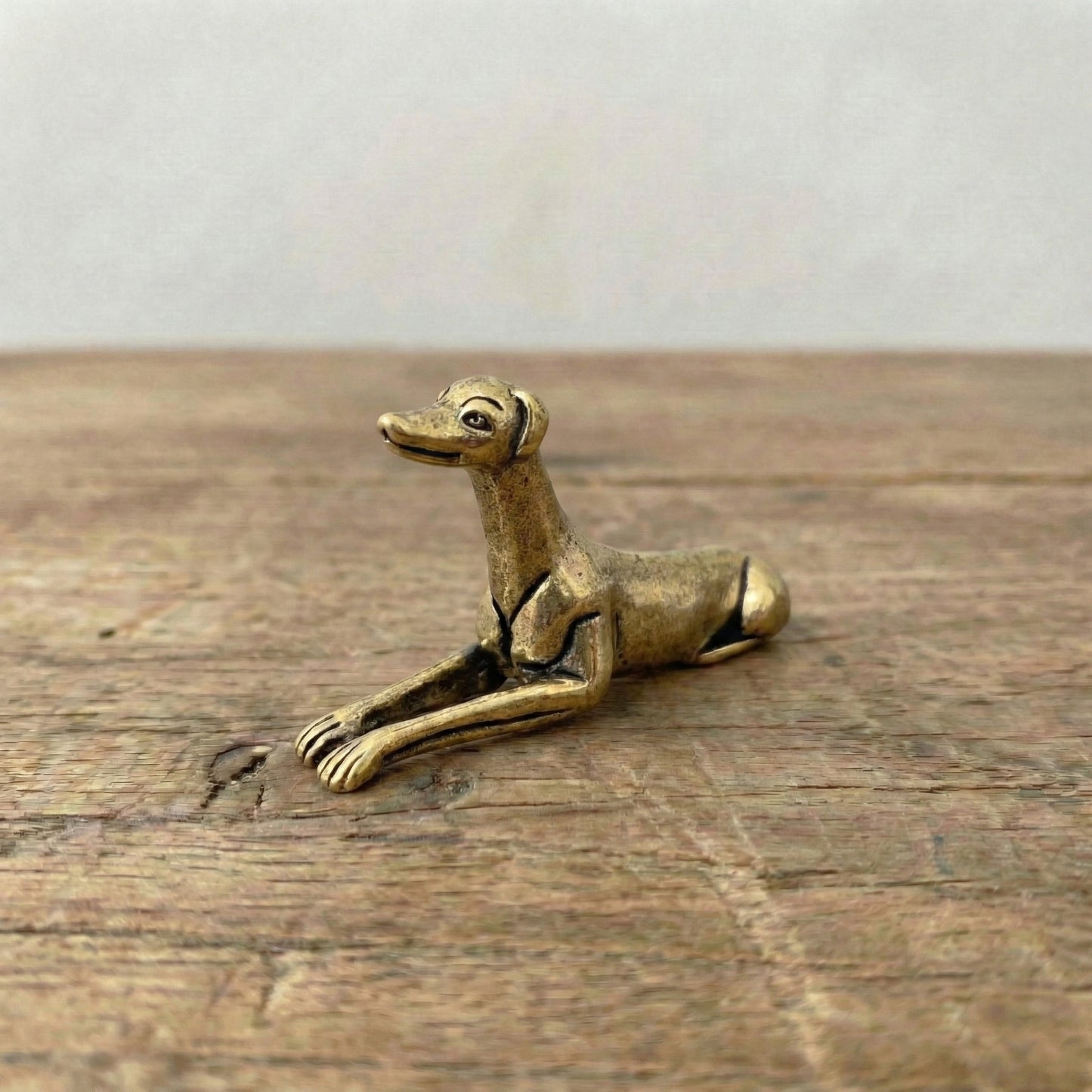 The Graceful Sentinel miniature brass greyhound held in hand to show scale, with sleek silhouette and golden patina