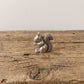 squirrel netsuke holding a nut, standing on a cut log 