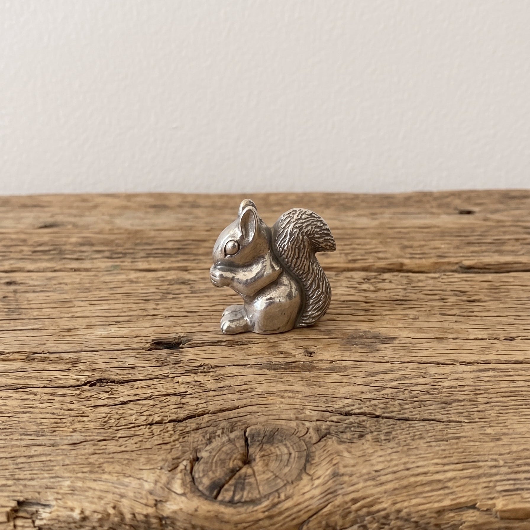 squirrel netsuke holding a nut, standing on a cut log 