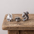 Set of three pewter netsuke figurines — a rabbit, a curled hedgehog, and a squirrel — photographed together on a gray background