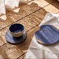 	Blue stoneware plates holding scones, figs and jam on a sunlit wooden table