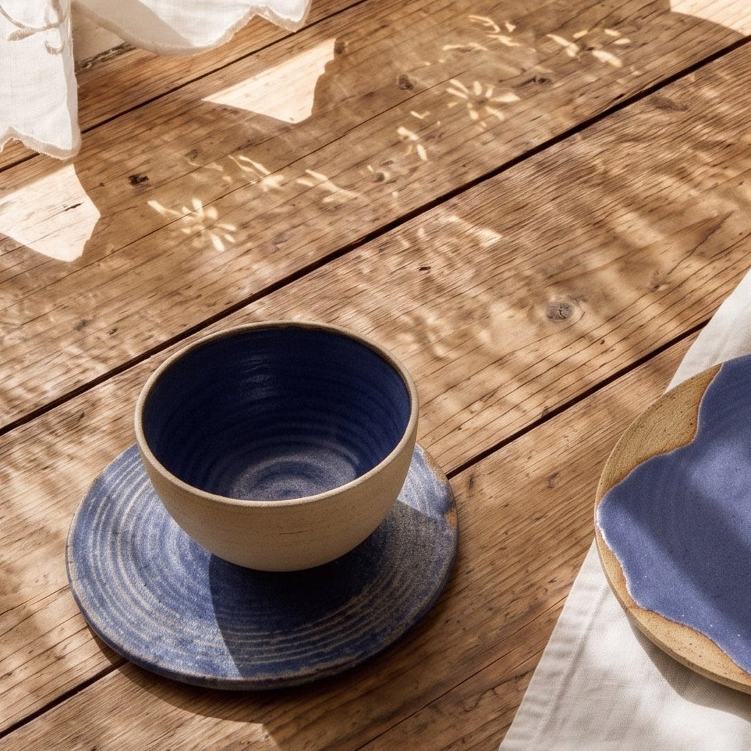 	Blue stoneware plates holding scones, figs and jam on a sunlit wooden table