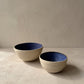 Two stoneware bowls, one tilted to show the blue glazed interior with visible potter's wheel rings