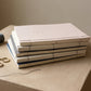 Stack of WILLAGE hand-bound journals showing Japanese stab binding with thread and scissors on stone surface