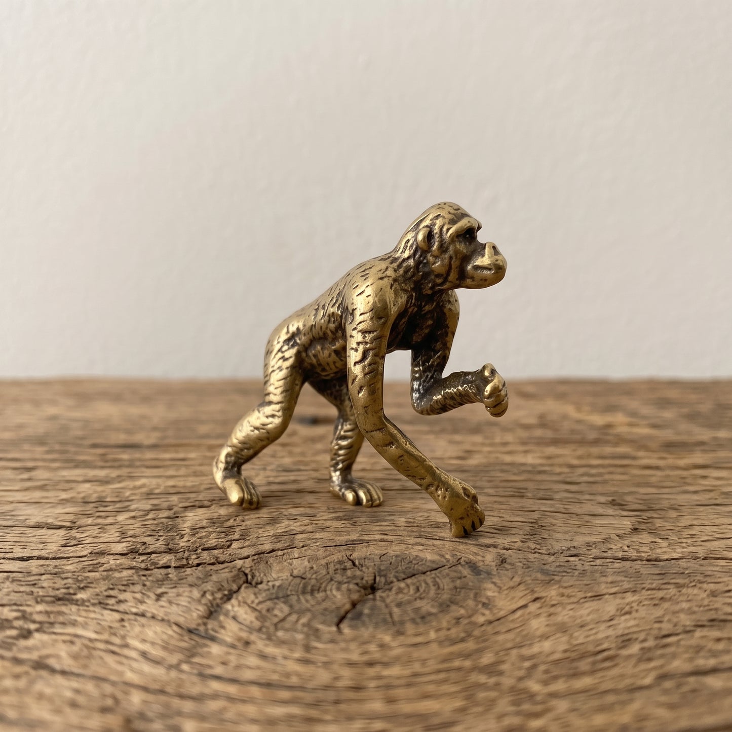 Side view of a brass ape figurine mid-stride 