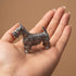 Pewter Scottish Terrier figurine standing in an open palm, showing its palm-sized scale and detailed wiry coat