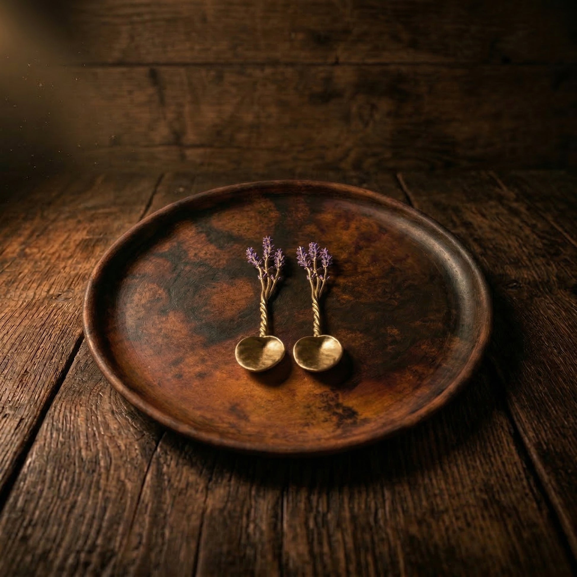 Lavender pewter serving spoon set of 2 displayed on handmade clay plate on rustic dark wood table