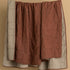 Hand-stitched reversible European linen quilt in oatmeal and cinnamon brown hung on a line showing both sides, with cross-stitch and running dash detail, from WILLAGE
