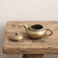 The Little Pot brass teapot with the lid removed, showing the hollow interior and antiqued finish