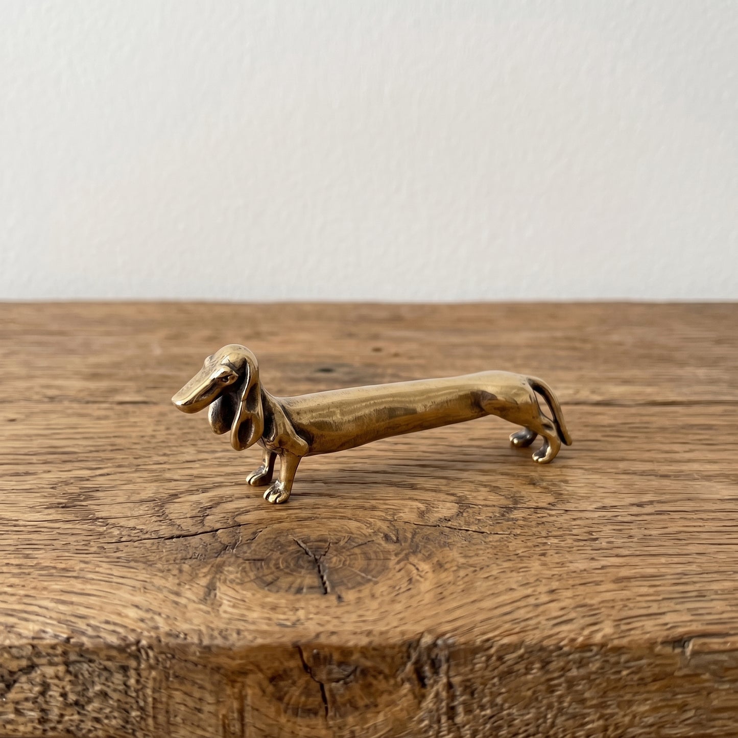 The Long Fellow miniature solid brass dachshund figurine stretched long with draped ears, warm brass finish