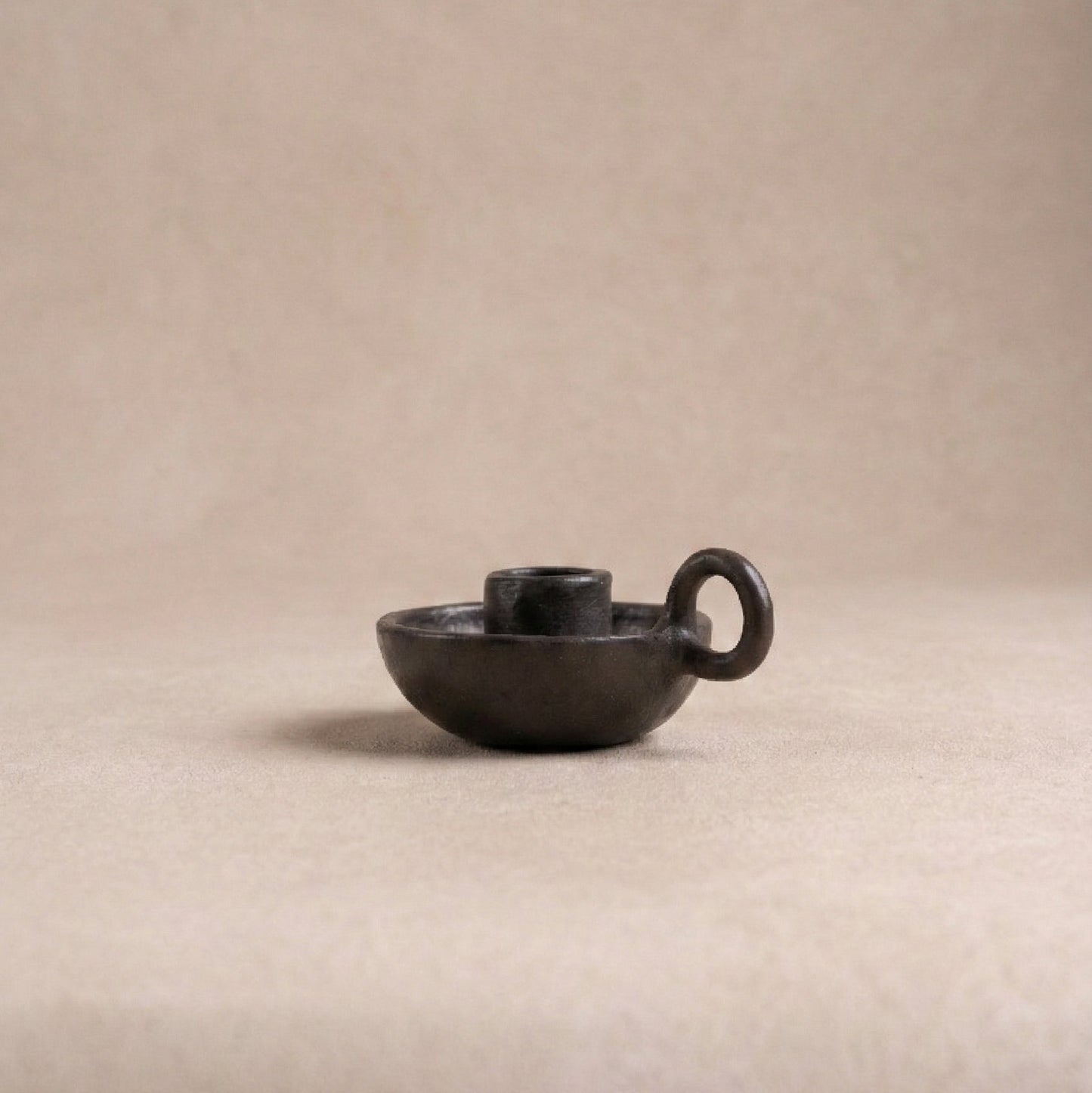 Longpi chamberstick candle holder showing curved finger loop handle and metallic black serpentinite stone finish