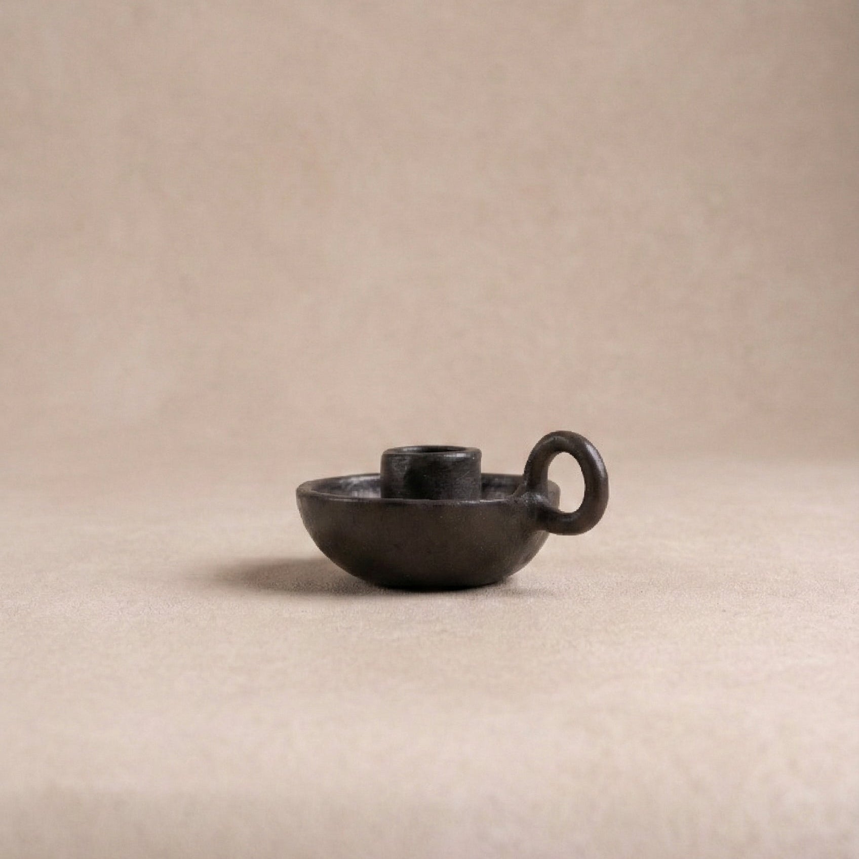 Longpi chamberstick candle holder showing curved finger loop handle and metallic black serpentinite stone finish