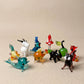 The Enchanted set of 10 miniature lampworked glass figurines including teal whale, white goat, blue parrot, red mushroom, green cat, black puppy, amber horse, and red fox, by Glass by Iness