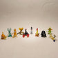 The Storybook set of 10 miniature lampworked glass figurines including orange snail, teal rabbit, yellow cat, cobra, snowman-dog, rooster, mole, frog prince, and golden cat, by Glass by Iness