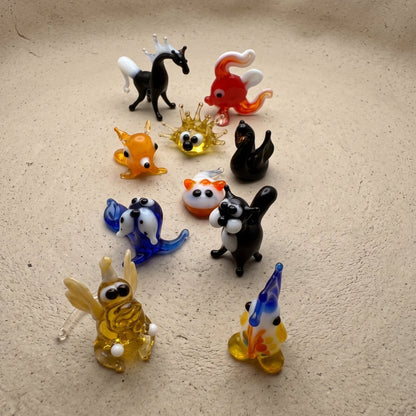 The Wild Ones set of 10 miniature lampworked glass figurines including black horse, red goldfish, orange fox, panda, blue dog, golden snail, black swan, and squirrel, by Glass by Iness