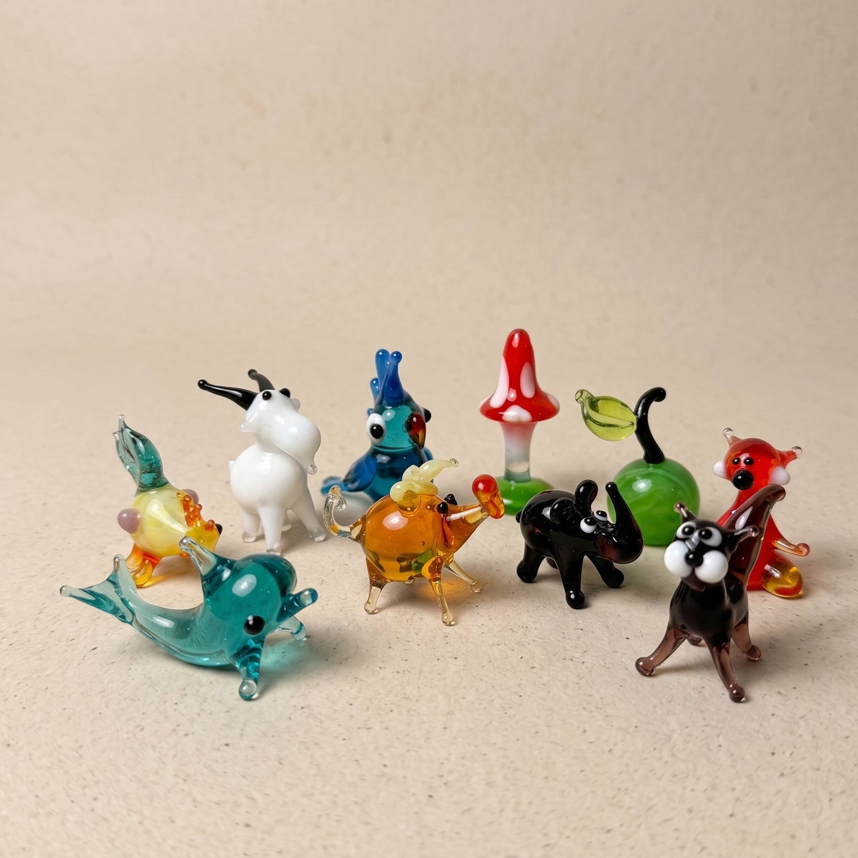 Collection of colorful glass animal figurines on a beige surface