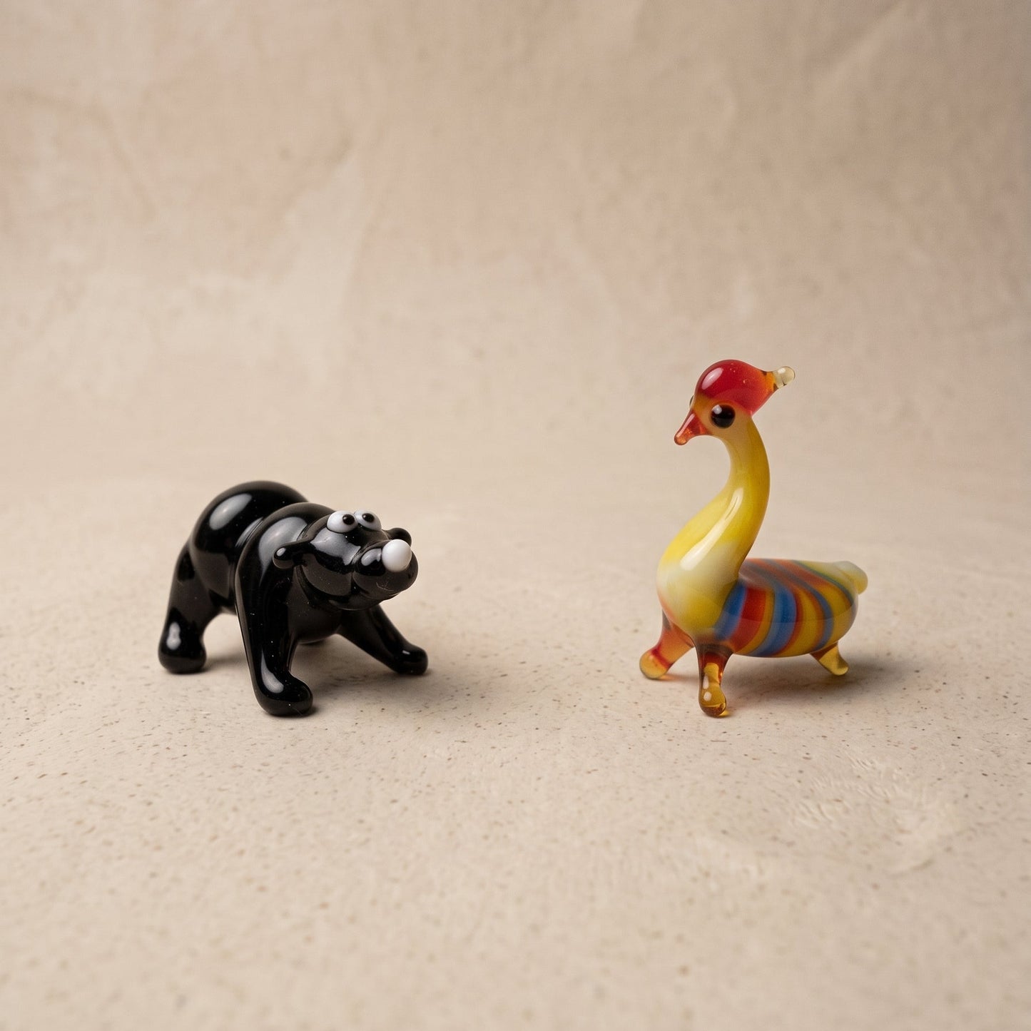 Close-up of miniature lampworked glass bear and striped rooster figurines showing face detail and color work, by Glass by Iness