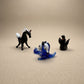 Three miniature lampworked glass figurines — black horse, blue spotted seal, and dark seal — showing variety of form and glasswork detail, by Glass by Iness