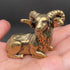  Solid brass ram figurine with large curled horns resting in an open palm, showing its small size and antique patina
