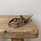 Front view of a brass crawfish figurine showing its two large pincers and detailed walking legs with antique patina
