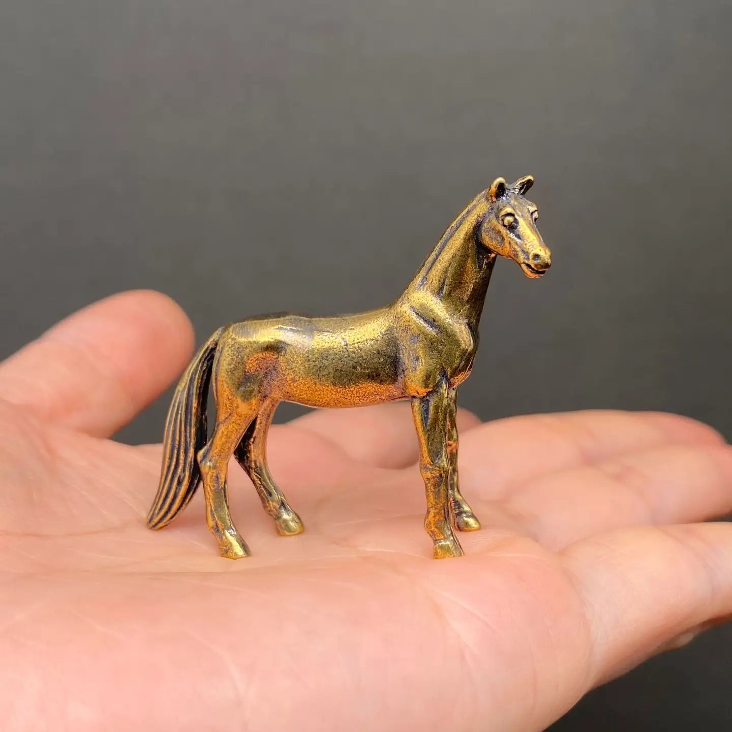 The Noble Spirit miniature brass horse showing side profile with detailed mane and golden patina against a neutral background