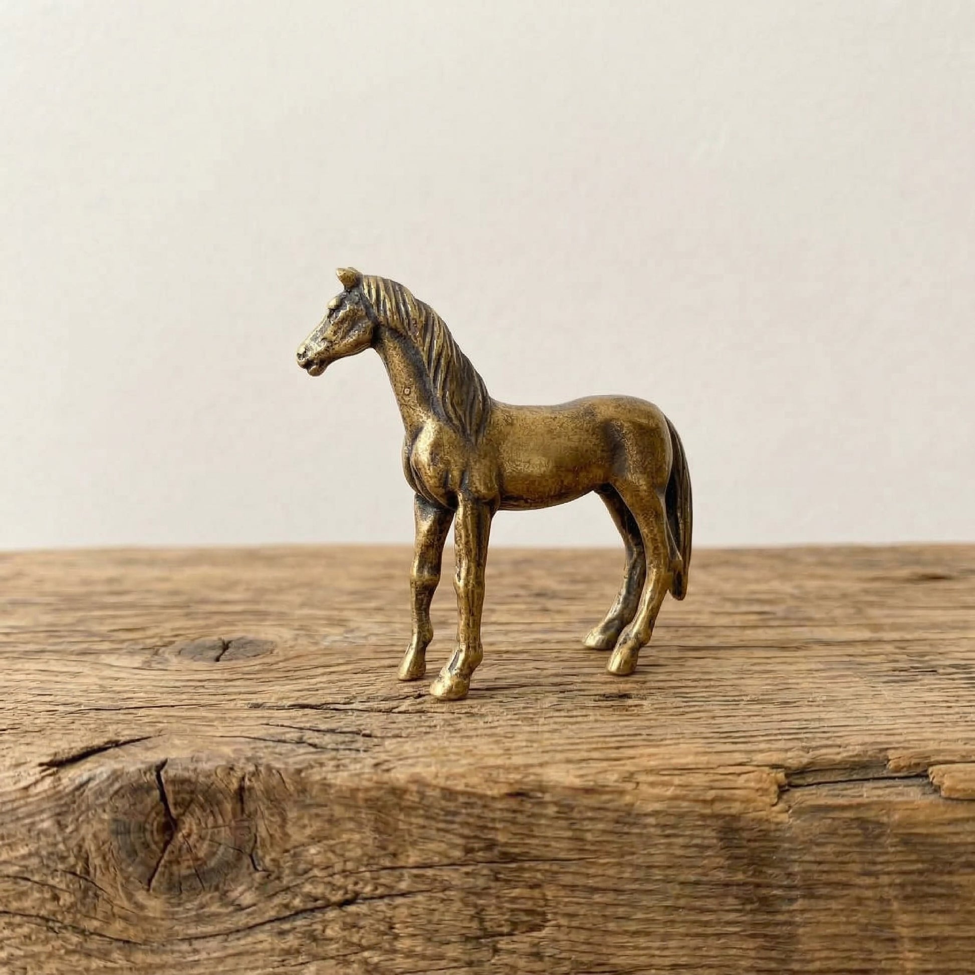 The Noble Spirit miniature brass horse standing on a wooden surface, with lean proportions and warm aged patina, from the WILLAGE Tiny Objects collection