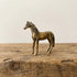 The Noble Spirit miniature brass horse standing on a wooden surface, with lean proportions and warm aged patina, from the WILLAGE Tiny Objects collection