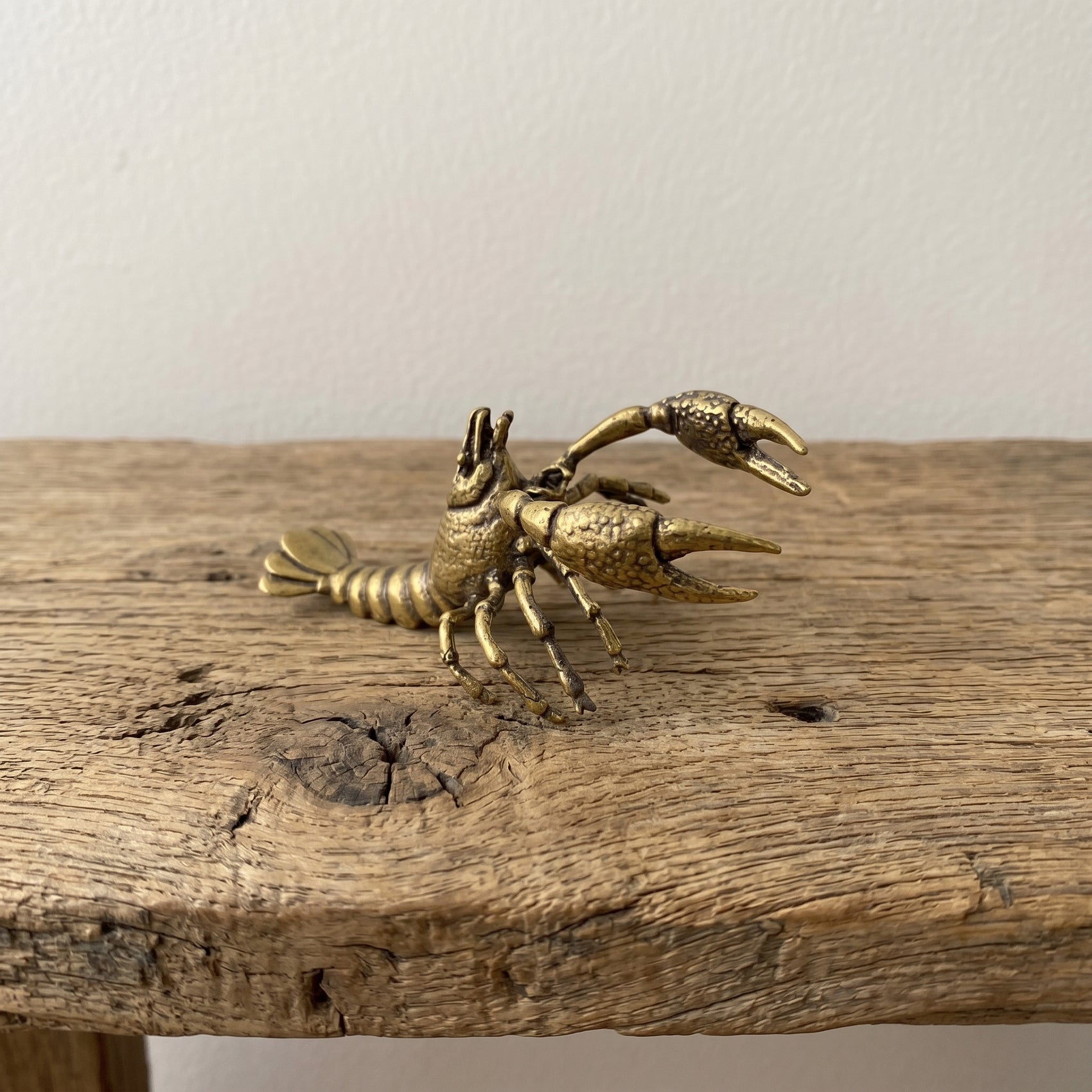 Solid brass lobster figurine with raised claws and fanned tail, antique patina finish, photographed on a gray background