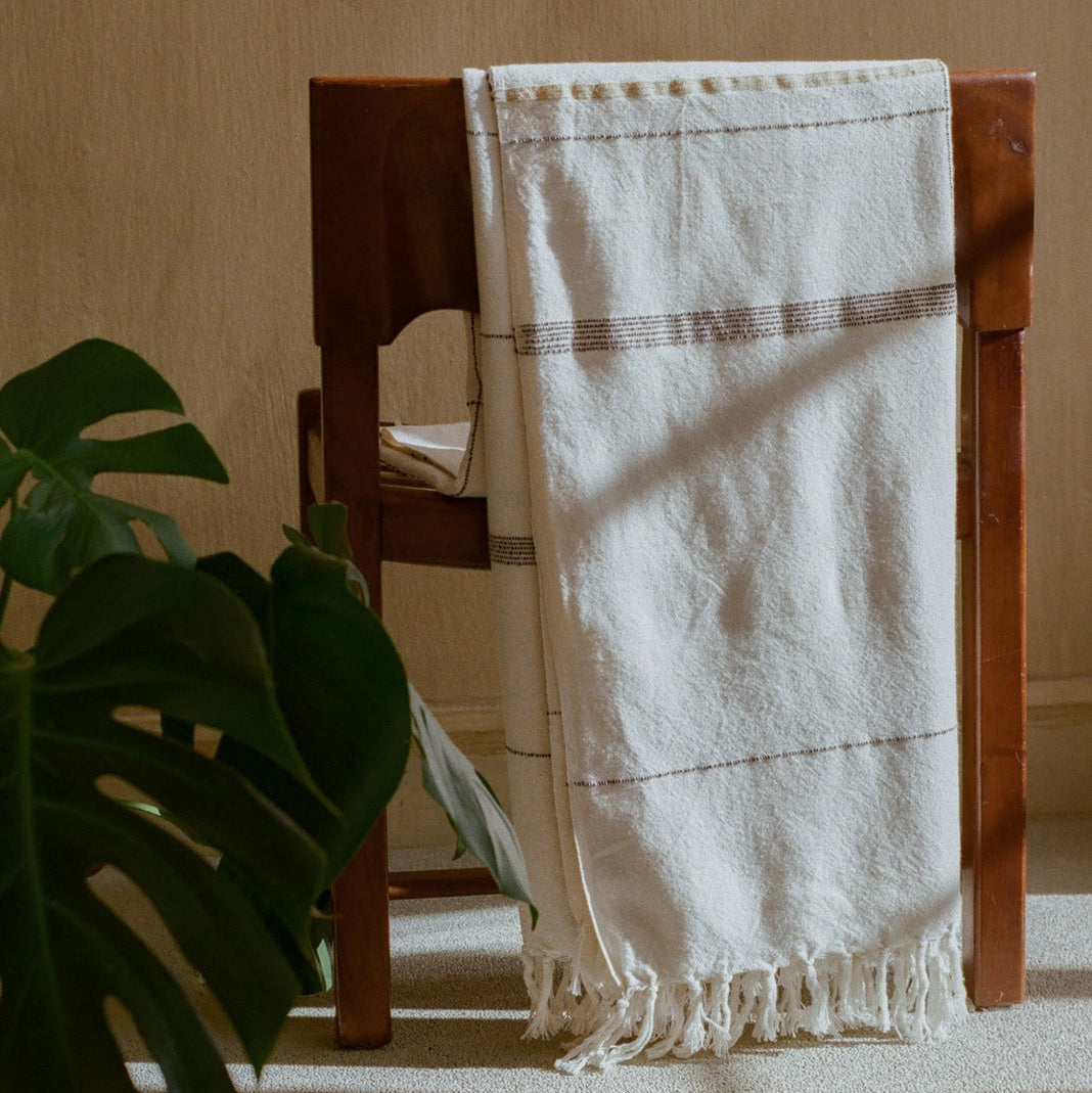 Organic cotton throw blanket draped over chair, hand-loomed in South Africa by Leila Atelier, from WILLAGE