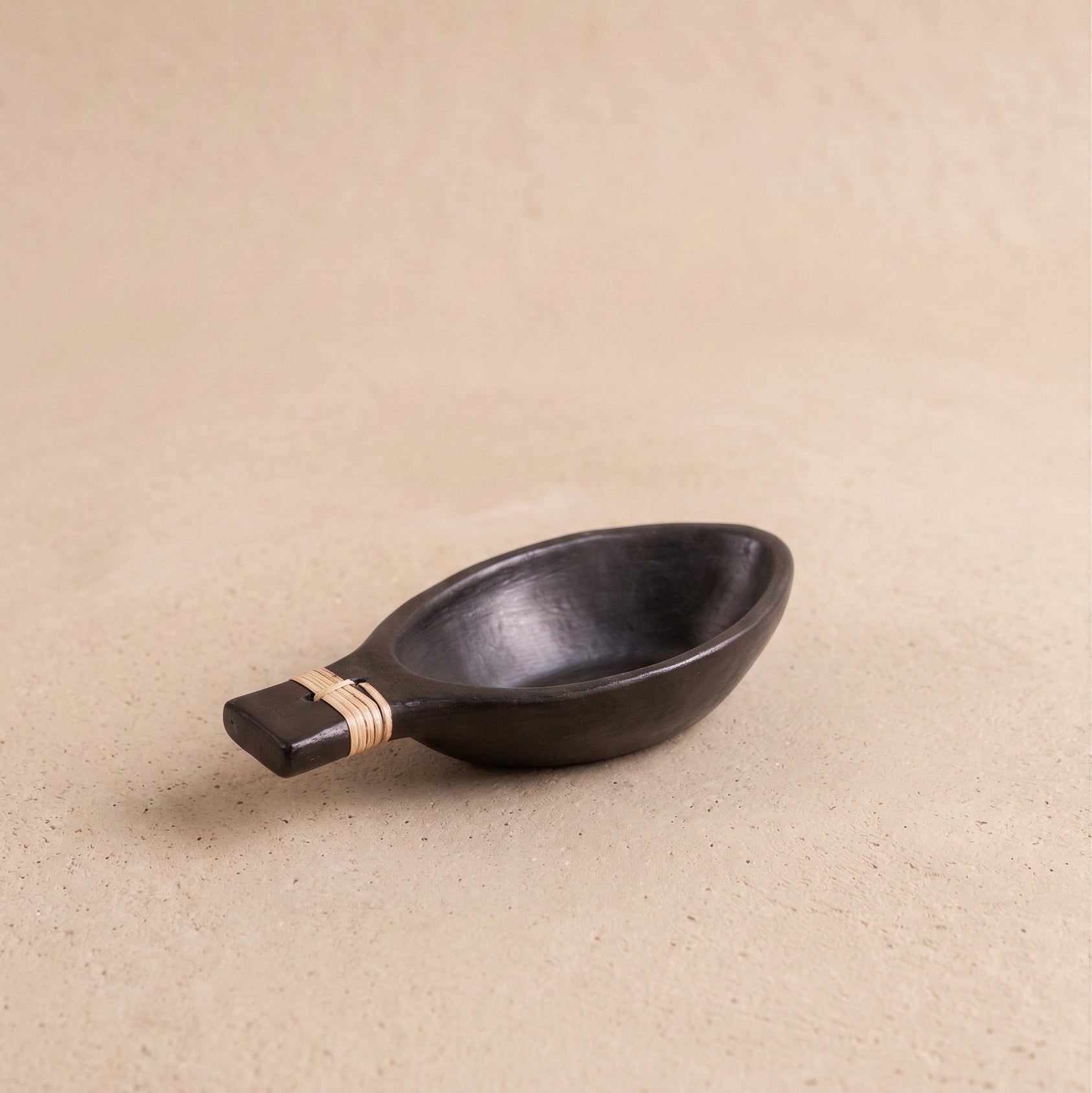 Patra serving bowl in Longpi black pottery showing woven handle detail and metallic black serpentinite stone finish