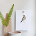  Magnetic beech wood wall holder gripping a bird art print on a white wall, held in place between two wooden blocks