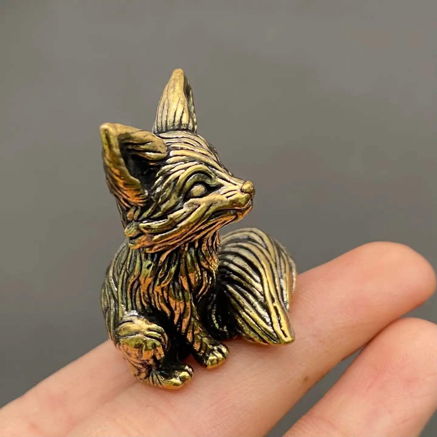 The Playful Kit miniature brass baby fox held in hand to show scale, with detailed fur texture and golden patina