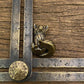 The Playful Kit miniature brass baby fox shown with ruler for scale, approximately 40 mm tall, with detailed fur texture and aged patina on a wooden surface