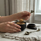 Pomegranate pewter serving spoon scooping brown sugar from handmade bowl on linen tablecloth