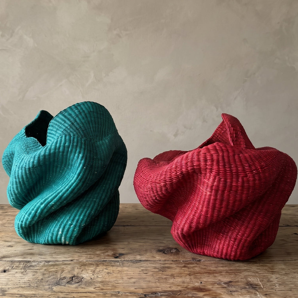 Red and green Bolga sculpture baskets side by side, showing two handwoven elephant-grass forms by Nanasei Agyemang