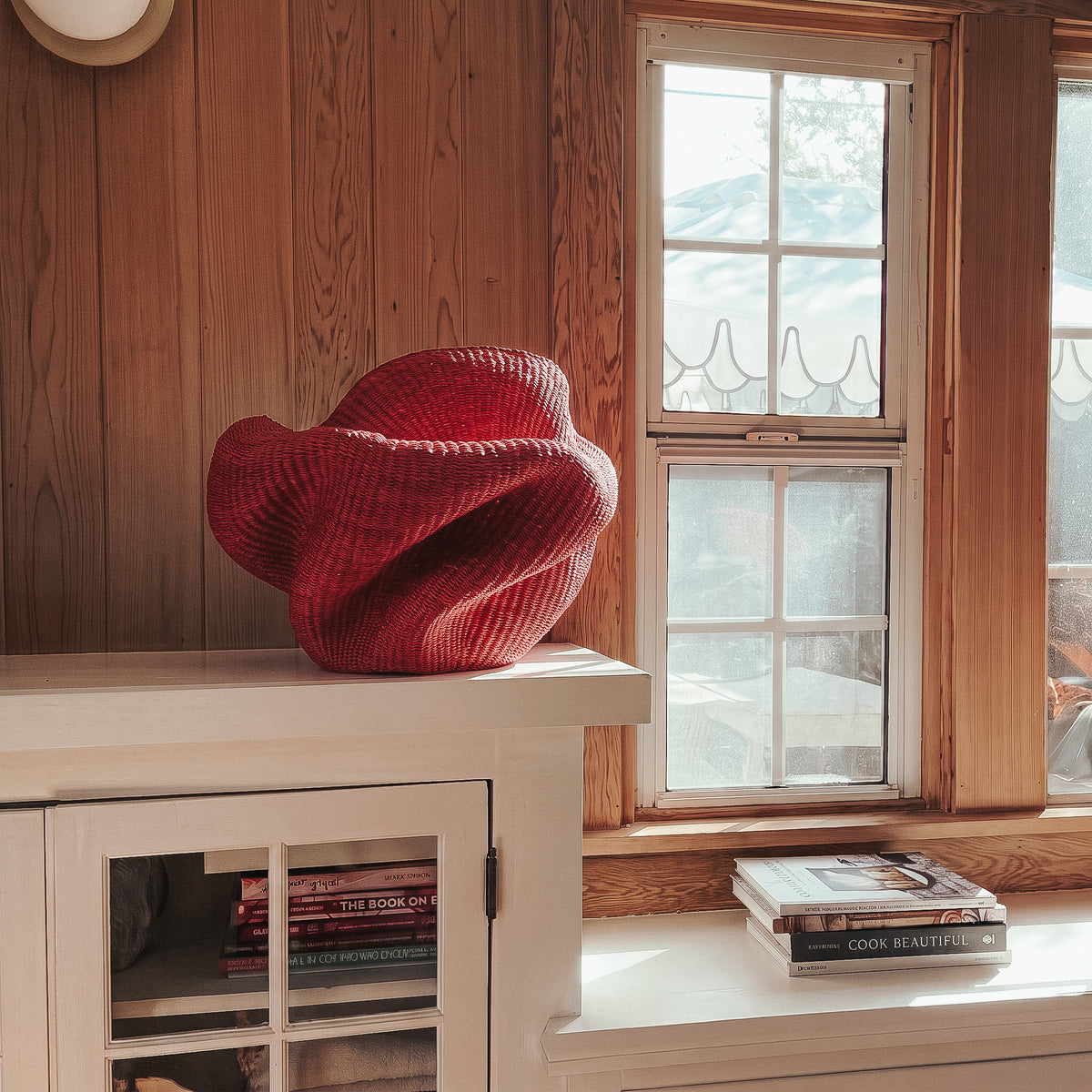 Red Bolga sculpture basket styled on a white stair newel post in a bright living room