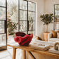 Red Bolga sculpture basket styled on a white stair newel post in a bright living room