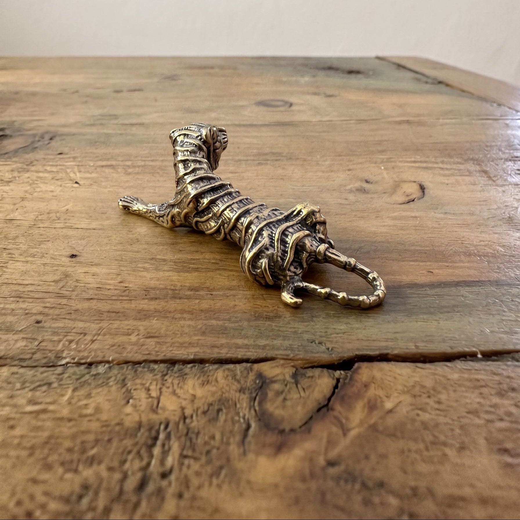 Three-quarter view of The Prowler brass tiger in an open palm showing the striped detail