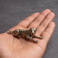 The Prowler brass tiger held in a hand to show its small size, about 1.8 inches long