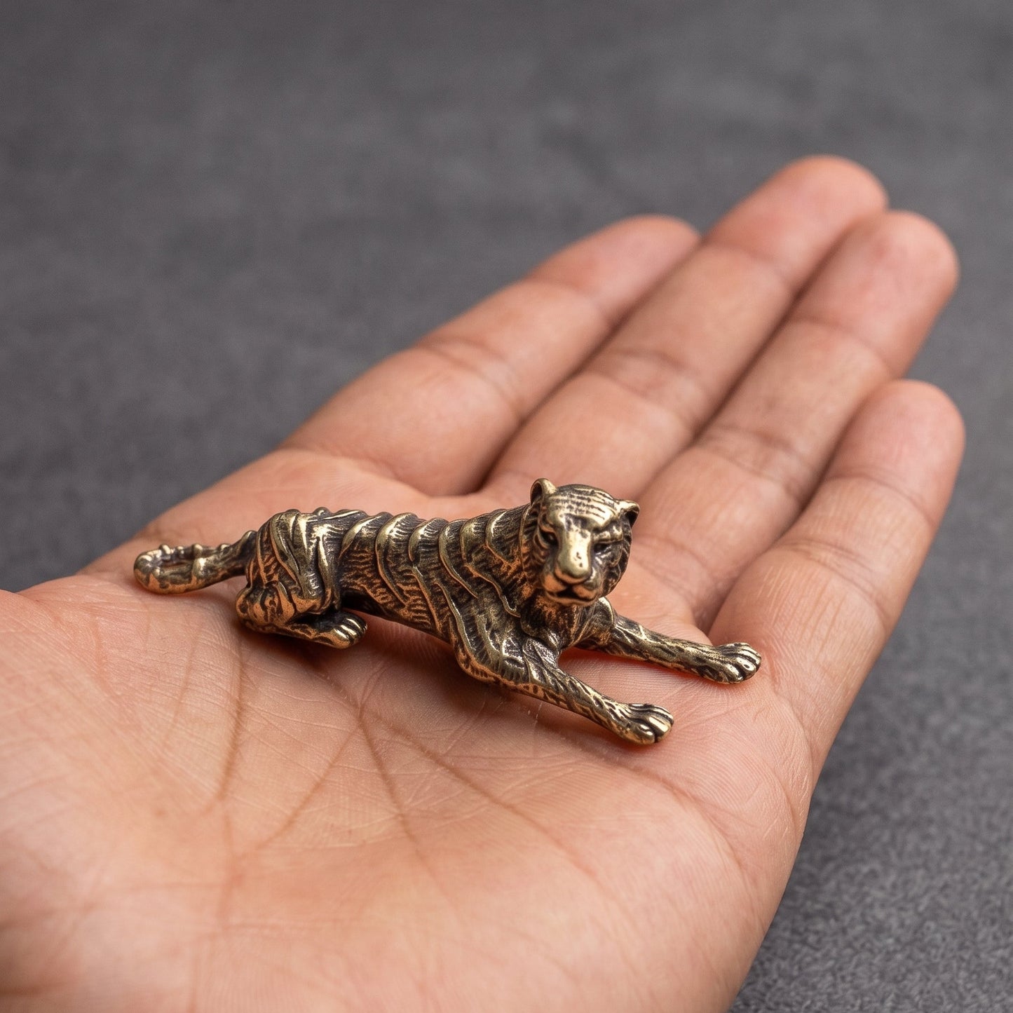 The Prowler brass tiger held in a hand to show its small size, about 1.8 inches long