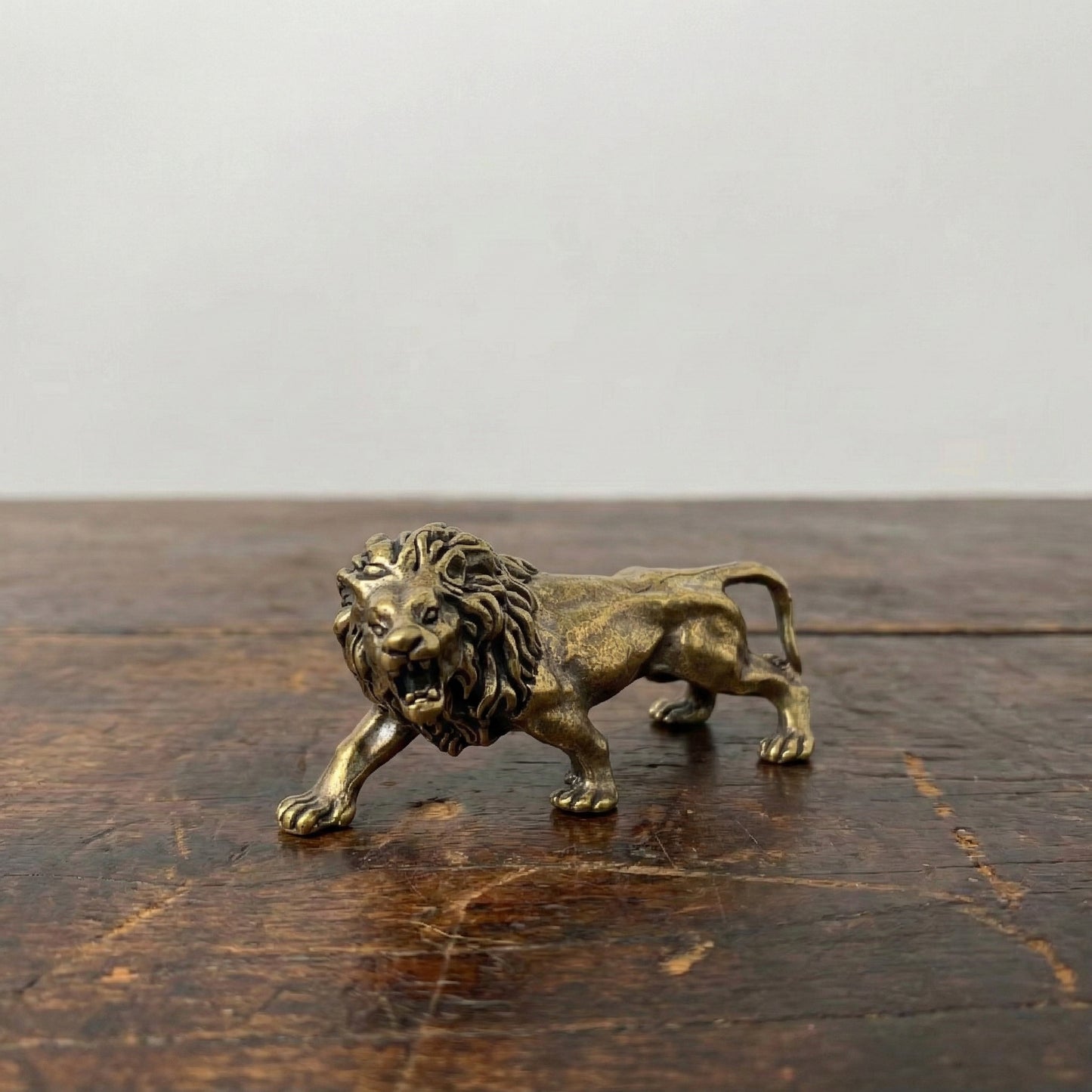 The Quiet Sovereign miniature brass lion figurine in mid-stride walking pose with detailed mane, solid brass with aged patina, from WILLAGE Tiny Objects collection