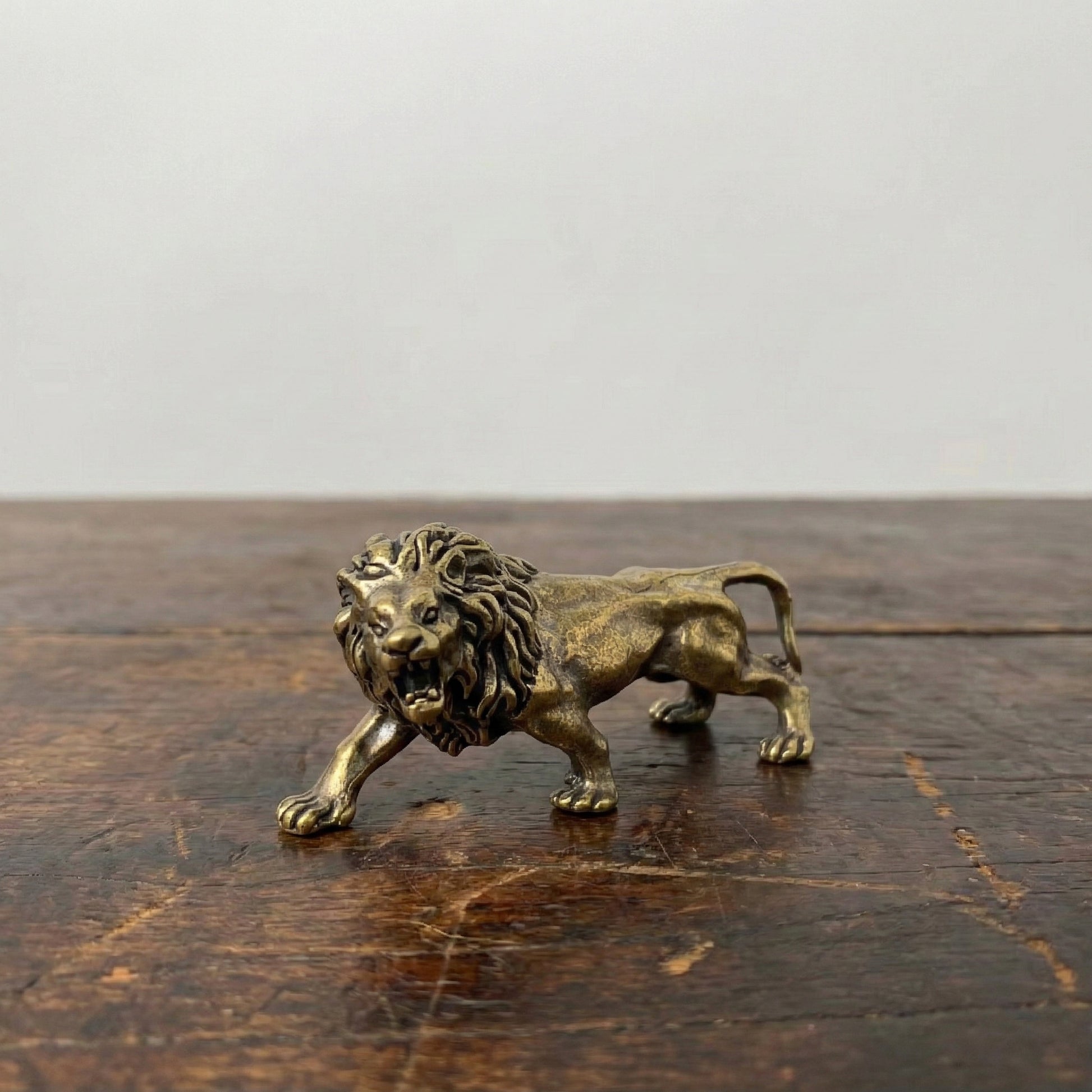 The Quiet Sovereign miniature brass lion figurine in mid-stride walking pose with detailed mane, solid brass with aged patina, from WILLAGE Tiny Objects collection