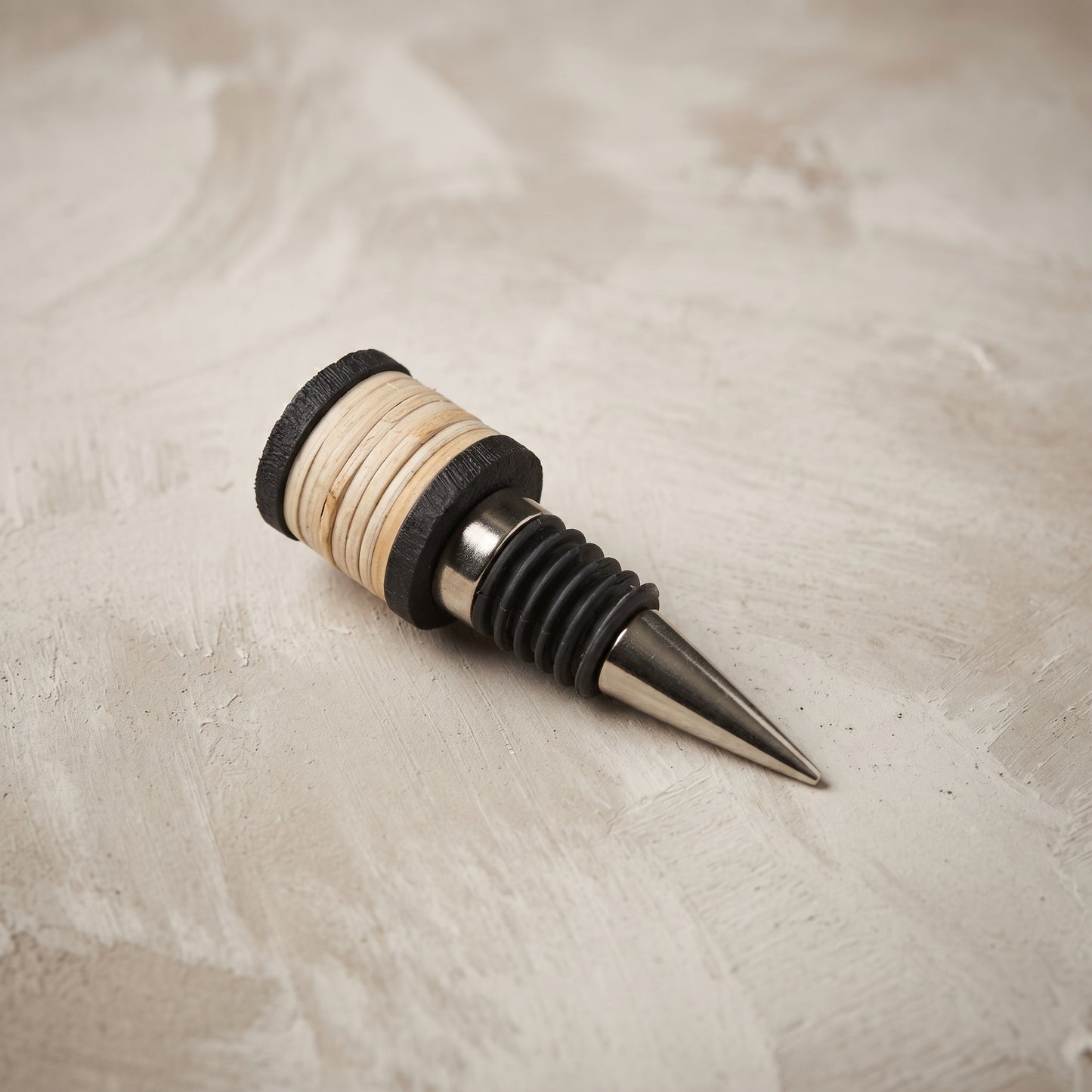 The Rattan Bottle Stopper, black mango wood cap hand-wrapped in natural rattan on a stainless steel stopper, from WILLAGE