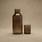Hand-hammered recycled glass carafe and tumbler set in amber and smoke, showing faceted surface texture, from WILLAGE