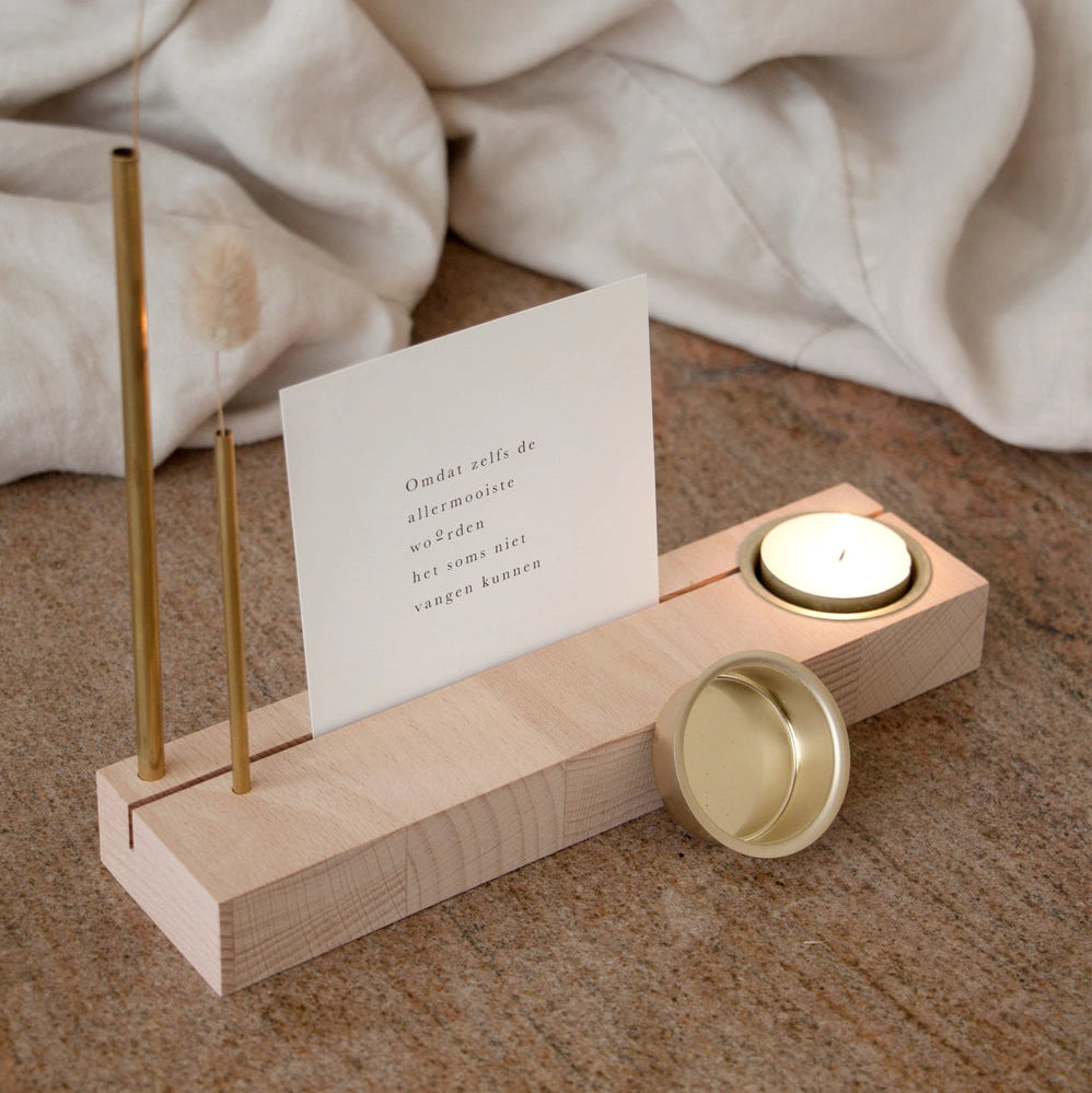 The Reflection Block beech wood display set with brass tubes, dried lagurus sprigs, and gold tea light holder, showing warm wood grain and ambient candle glow, from WILLAGE