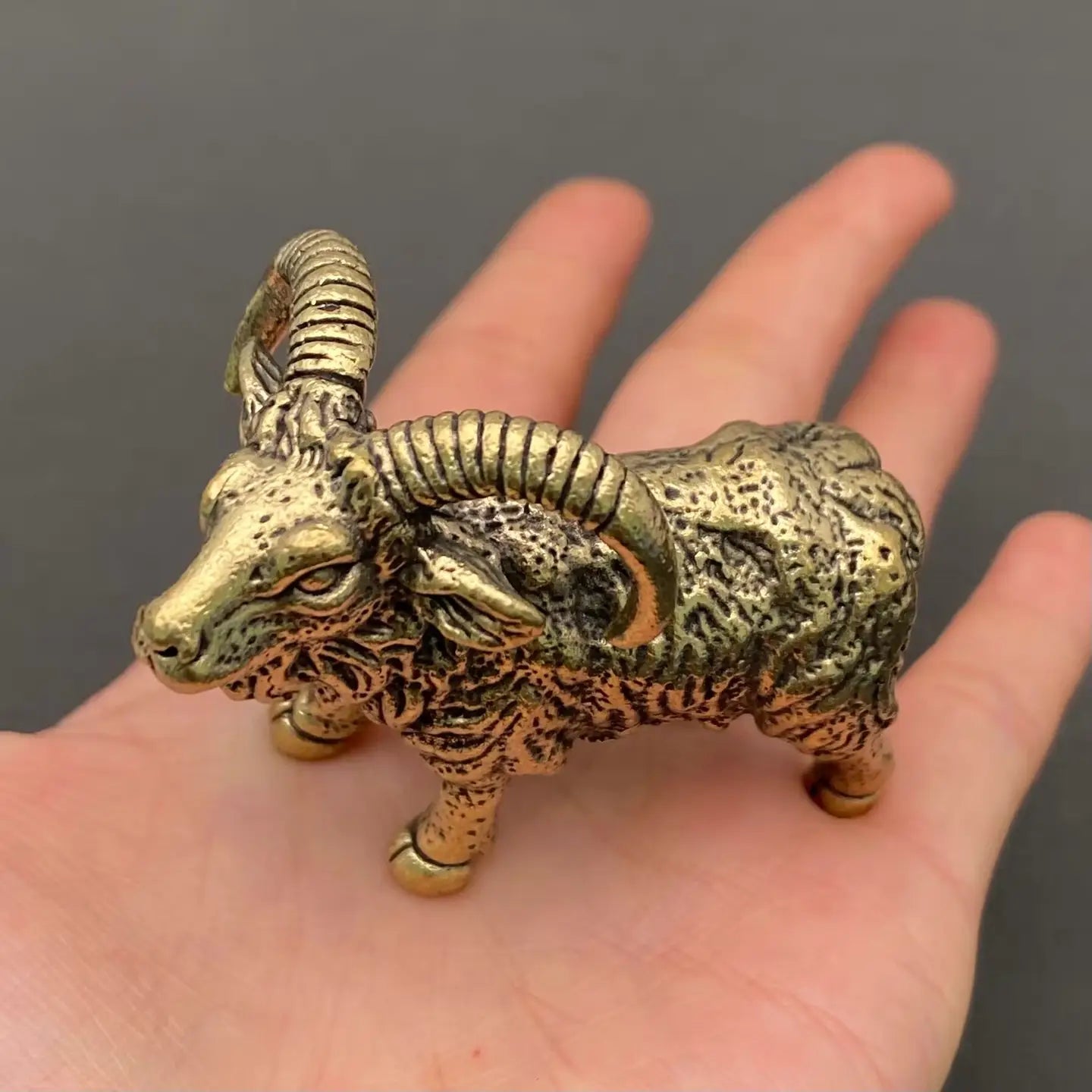 The Resilient Presence miniature brass ram showing horn curl detail and textured coat against a neutral background