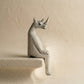 The Resting Rhino hand-carved wooden shelf sitter in a seated pose with dangling legs, carved from jacaranda wood by Kamba tribe artisans in Kenya, from WILLAGE